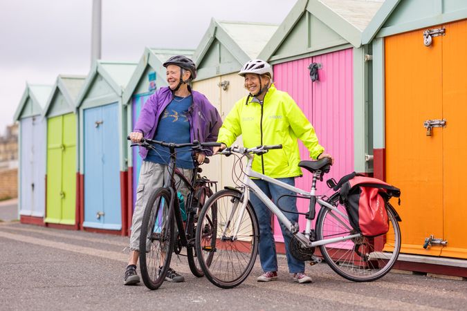 Two smiling older people standing with bikes looking away