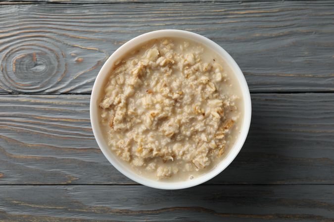 Bowl with oatmeal porridge on wooden background