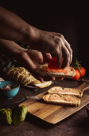 Crop person pouring tomato on toasts