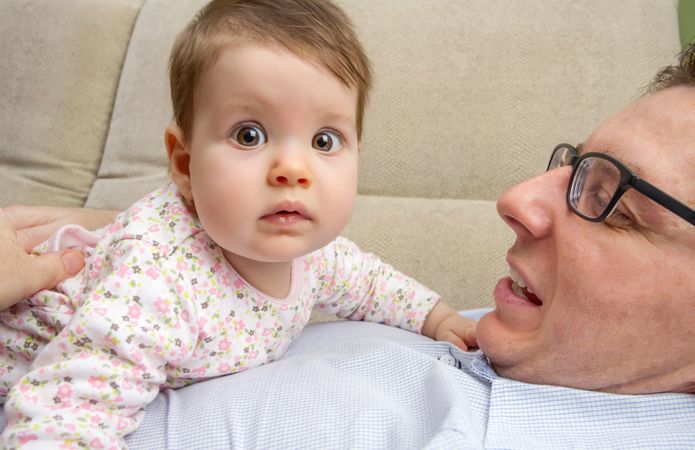 Baby with big eyes sitting on father's chest