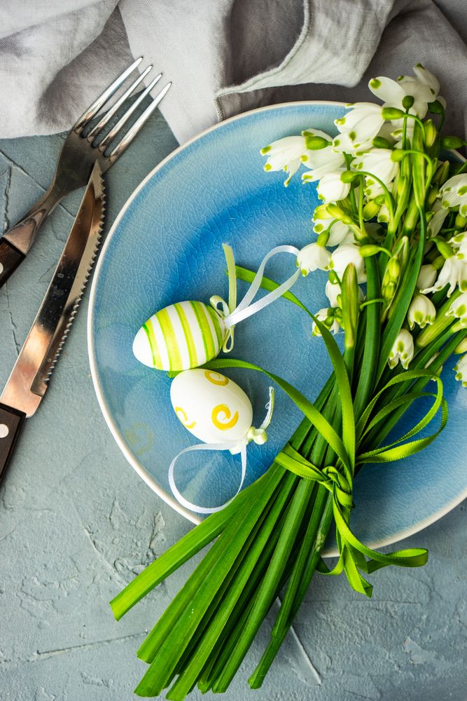 Top view of table setting for Easter dinner with egg decor and flowers