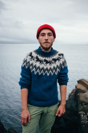 Portrait of man in woolen sweater on rugged Icelandic coast