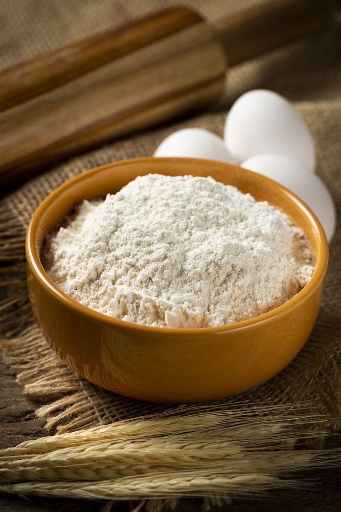 Bowl with wheat flour on the table.