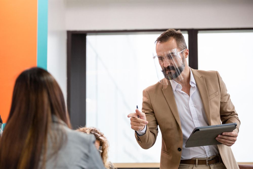 Male in face shield pointing at woman in office