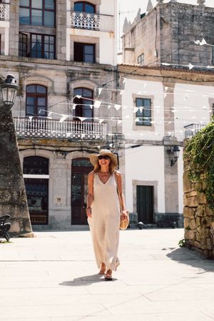 Woman in hat walking along sunny street