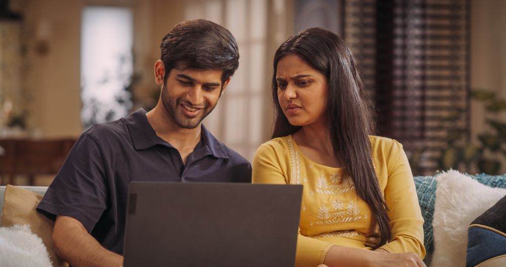 Indian Couple Using Laptop Computer at Home to do Online Shopping Together, Searching For Perfect Gifts
