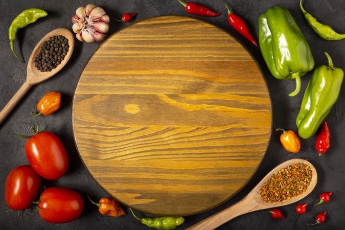 Empty pizza  board on the table with Ingredients for cooking. Tomatoes, various peppers, garlic and green peppers.