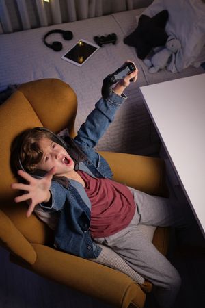 Joyful preteen boy rejoicing victory in videogame