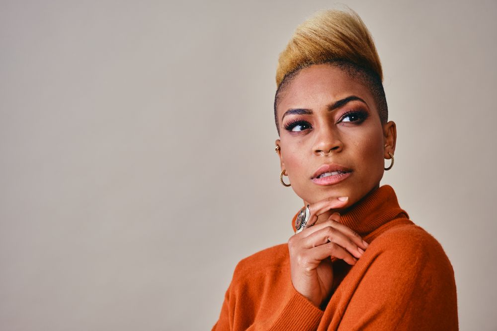 Studio shot of Black woman with her hand to her chin with short blonde hair