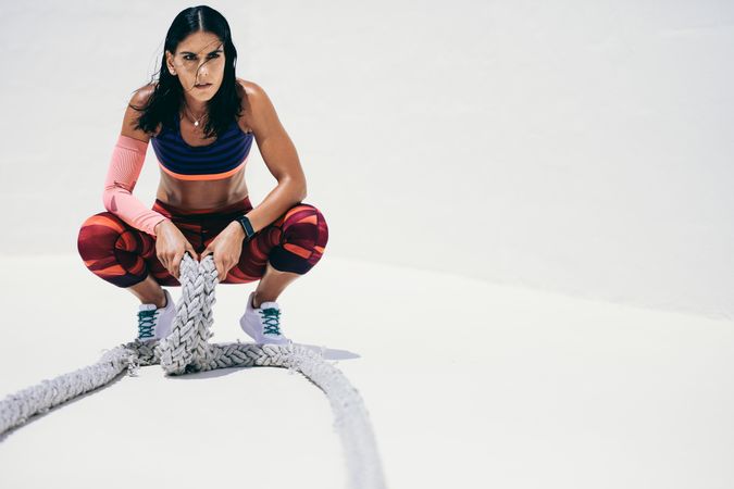 Athletic woman taking rest after workout using battle ropes