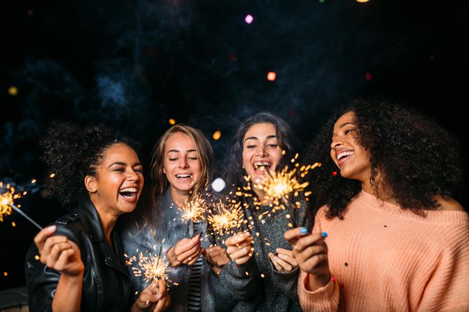Multi-ethnic group of laughing women celebrating with sparklers