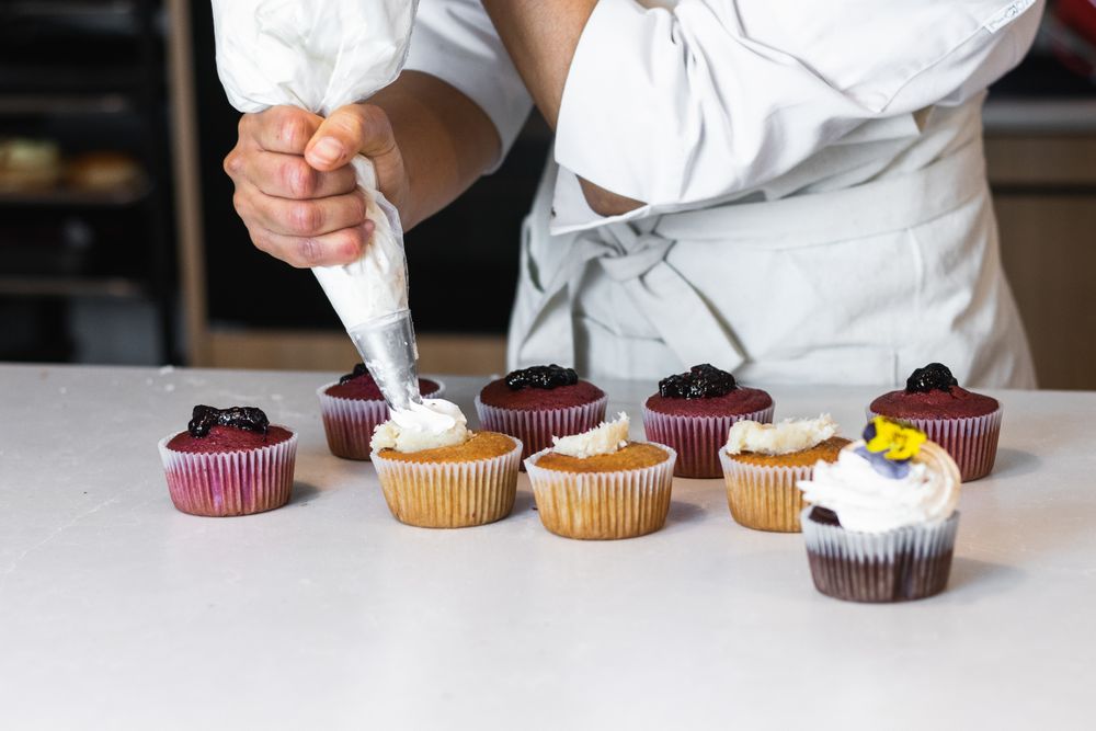 Crop cook decorating cupcakes with whipped cream