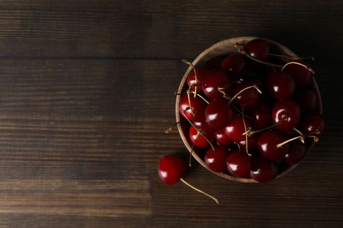 Ripe cherry fruits in a bowl on a wooden background