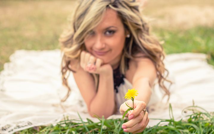 Romantic woman holding flower in the hand lying down outdoors