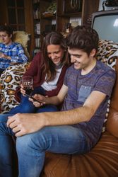 Young couple looking smartphone sitting on sofa