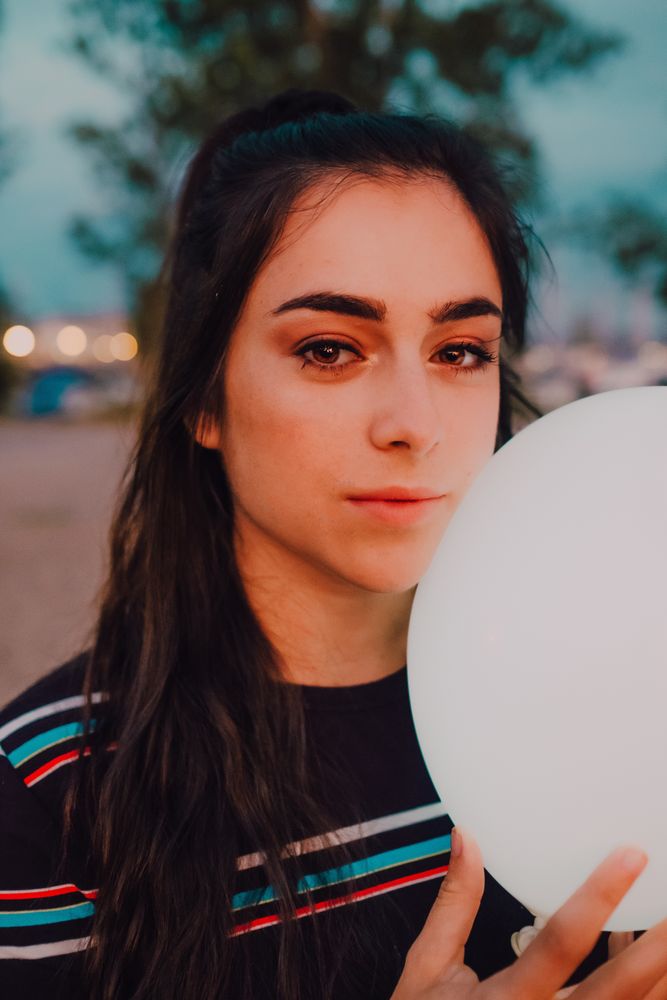 young female with white light balloon outside