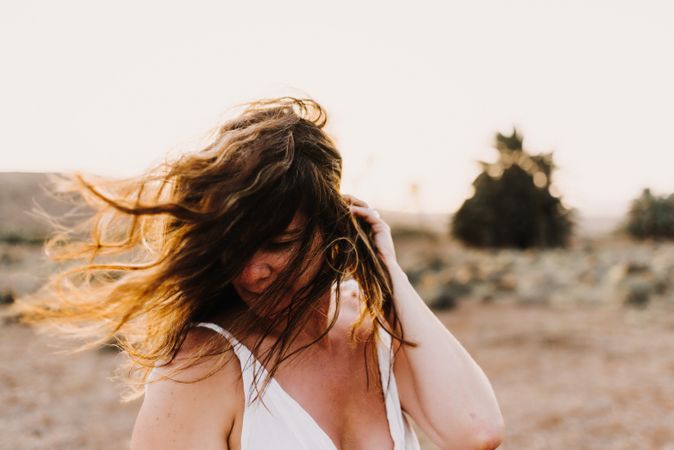 Woman in white dress in dry field in sunlight