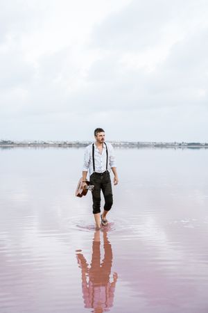 Musician holding guitar at seaside
