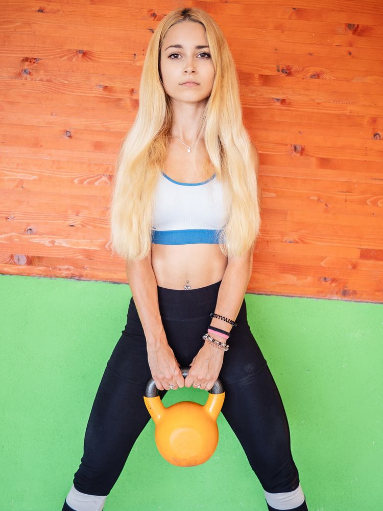 Young sportswoman with kettlebell in gym