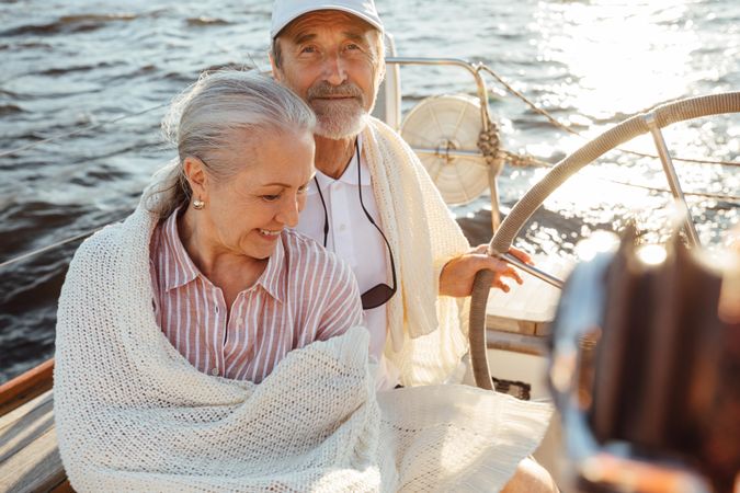 Happy older couple sitting by helm of boat