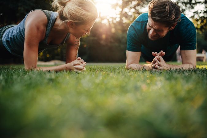 Fit young man and woman doing core training outdoors in morning