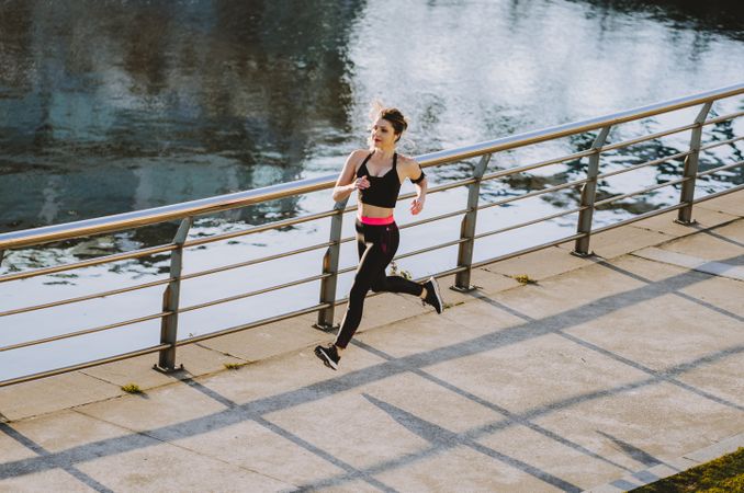 Woman running on embankment near water