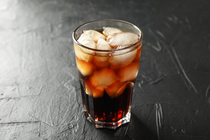 Glass of cold cola on cement background
