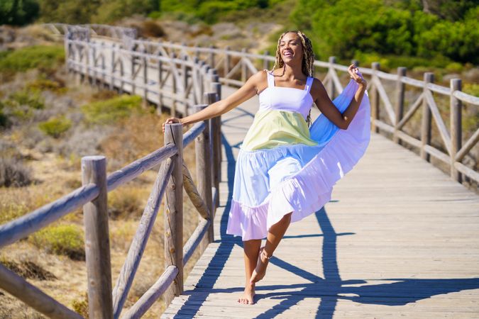 Joyful female dancing in colorful dress on a pedestrian walkway