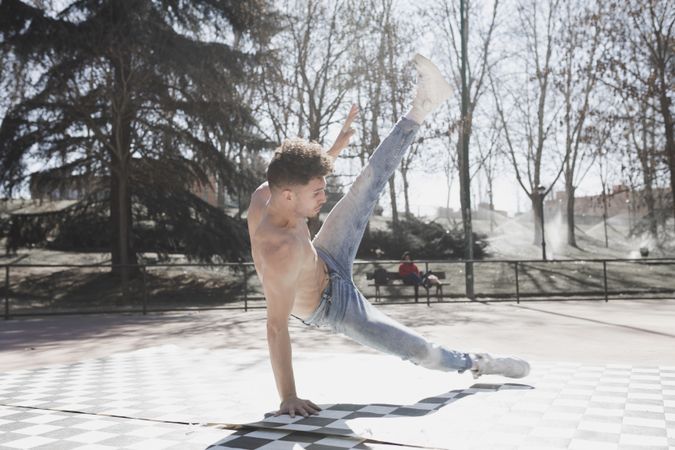 Shirtless man dancing break dance in park
