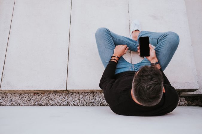 Adult stylish smiling man using a smartphone near grey wall