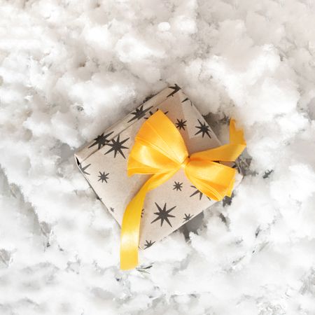 Present wrapped in yellow bow on snow