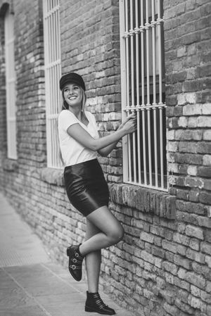 Smiling woman holding onto window railing in b&w