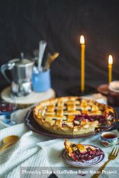 Homemade cherry pie on table with lit taper candles 0PqdN5