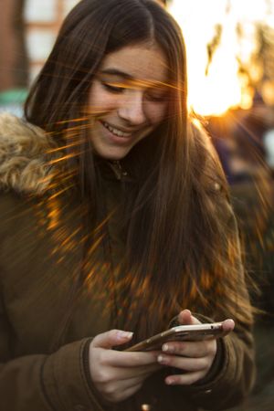Cheerful female with smartphone on street