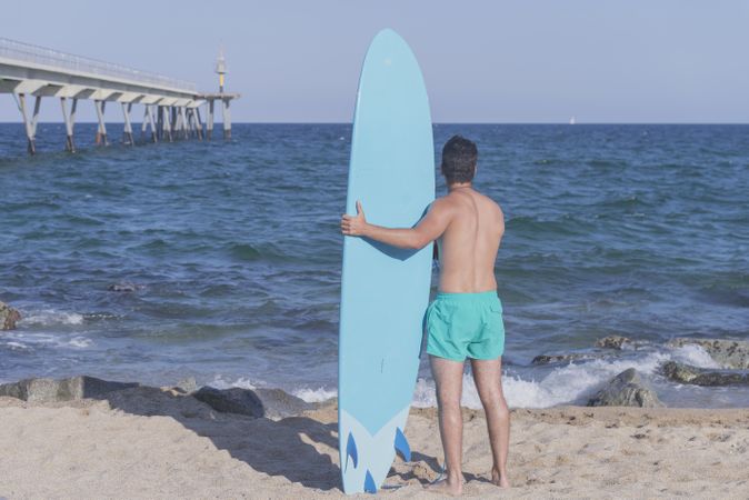 Male surfer holding his surfboard looking out to the view