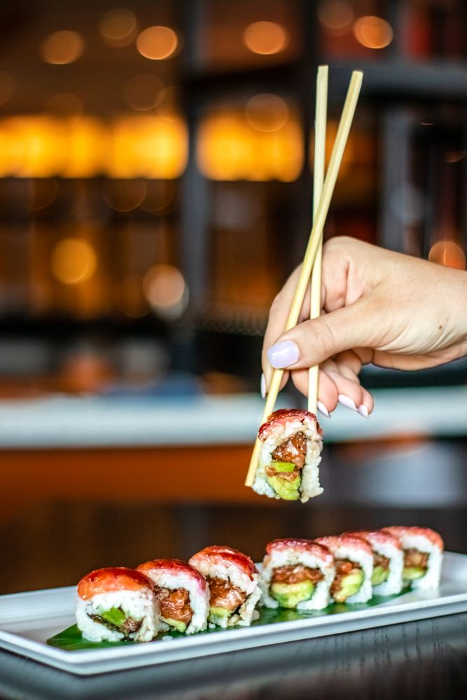 Person holding sushi with chopsticks