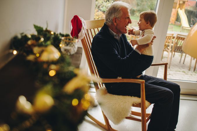 Mature man sitting on chair and playing with his grandson