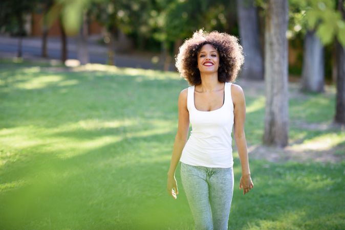 Young Black woman with afro hairstyle walking through park