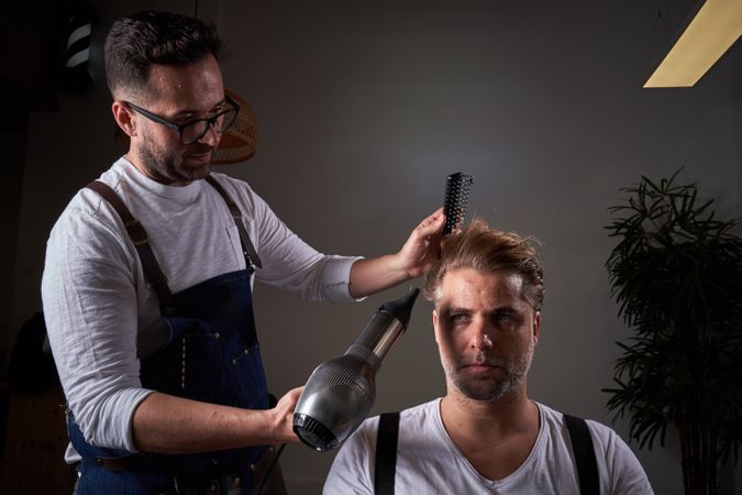 Concentrated barber drying hair of client