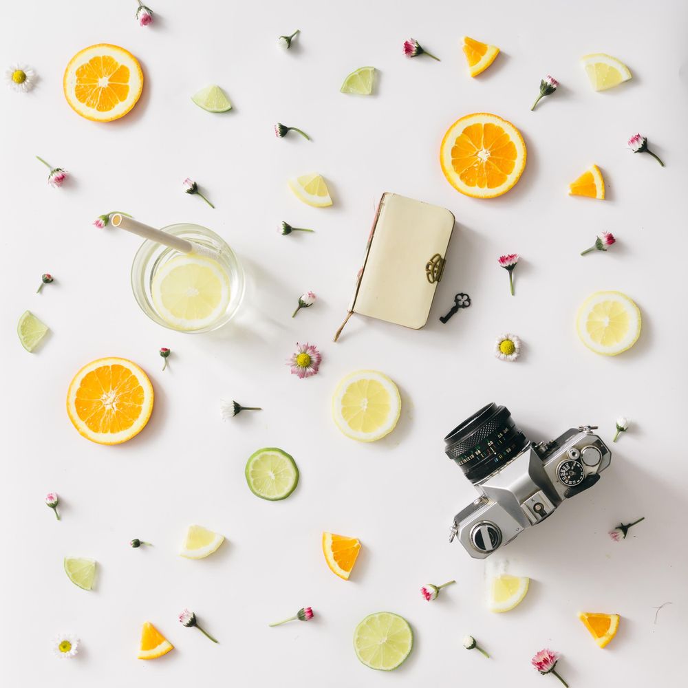 Colorful pattern made of orange, lemon, lime and flowers with lemonade and vintage camera