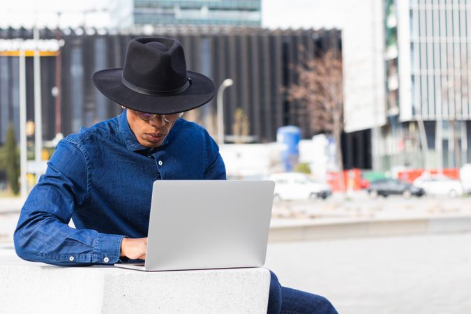 Serious male freelancer working on laptop in city