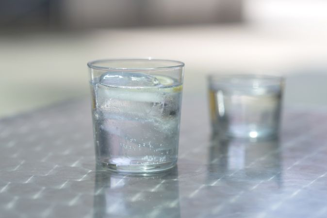 Two glasses of water with ice on a metallic table outdoors