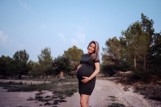 Charming pregnant woman standing on walkway in park