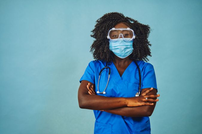 Black female healthcare professional wearing a face mask, protective eyewear, and stethoscope