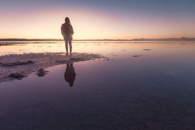 Woman admiring beautiful sky on empty beach