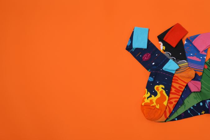 Bright socks with a print, in a pile on an orange background.