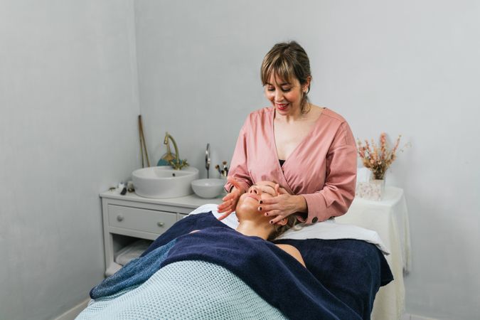 Smiling masseuse doing massage for woman in spa salon