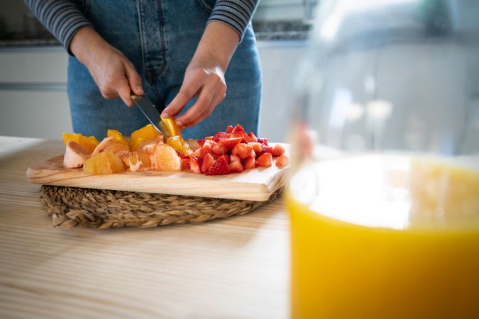Crop woman cutting fruits for smoothie