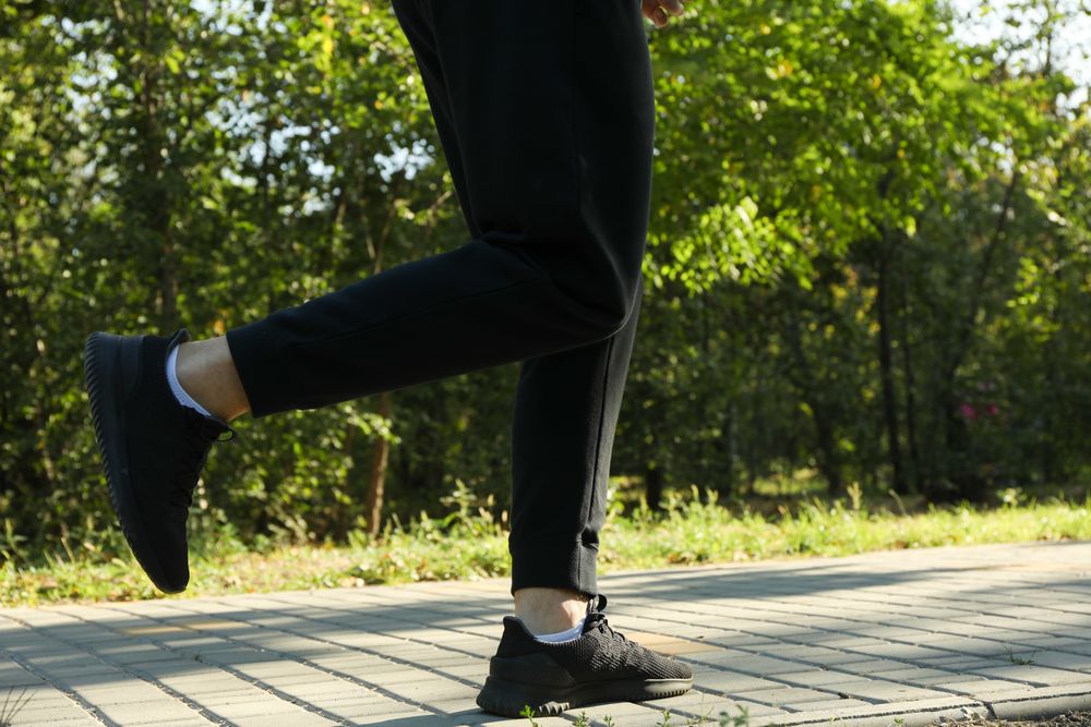 A man in a tracksuit running in the park in sunny morning