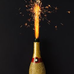 Golden champagne party bottle onbackground with fire sparklers